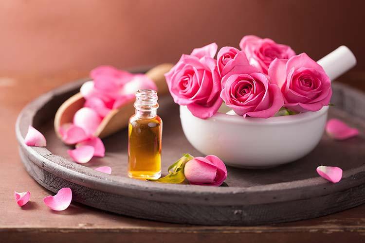 Bottle of Bulgarian rose oil beside Damask roses